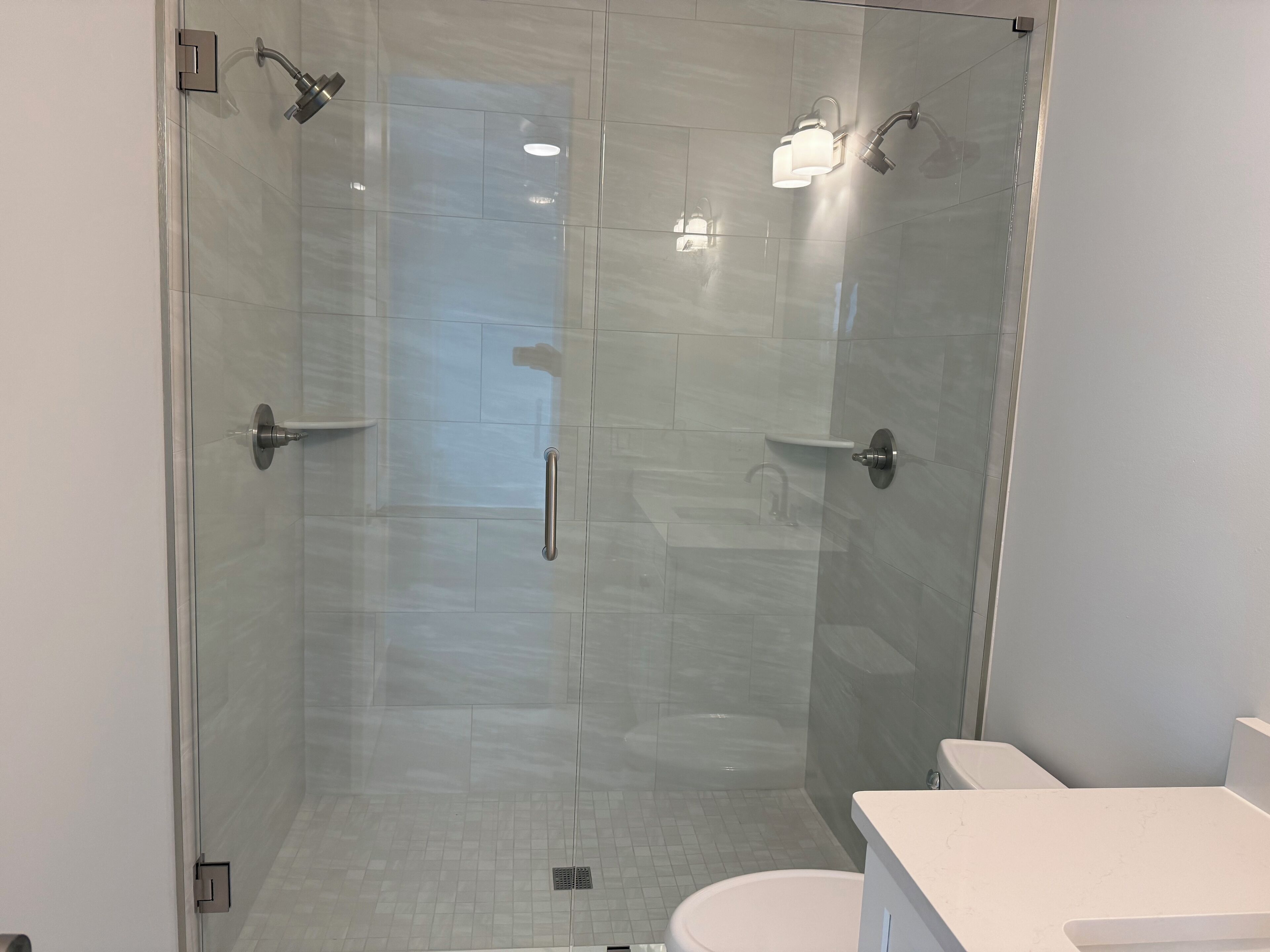 A modern bathroom with a glass-enclosed shower, a white toilet, and a white sink.