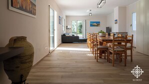 Een ruime eethoek met een houten tafel en stoelen, een grote vaas en een bank op de achtergrond.