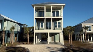 Un edificio de dos pisos con un balcón en el nivel superior, rodeado de palmeras.