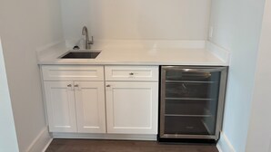Cocina compacta con lavaplatos, pileta y muebles de cocina blancos.