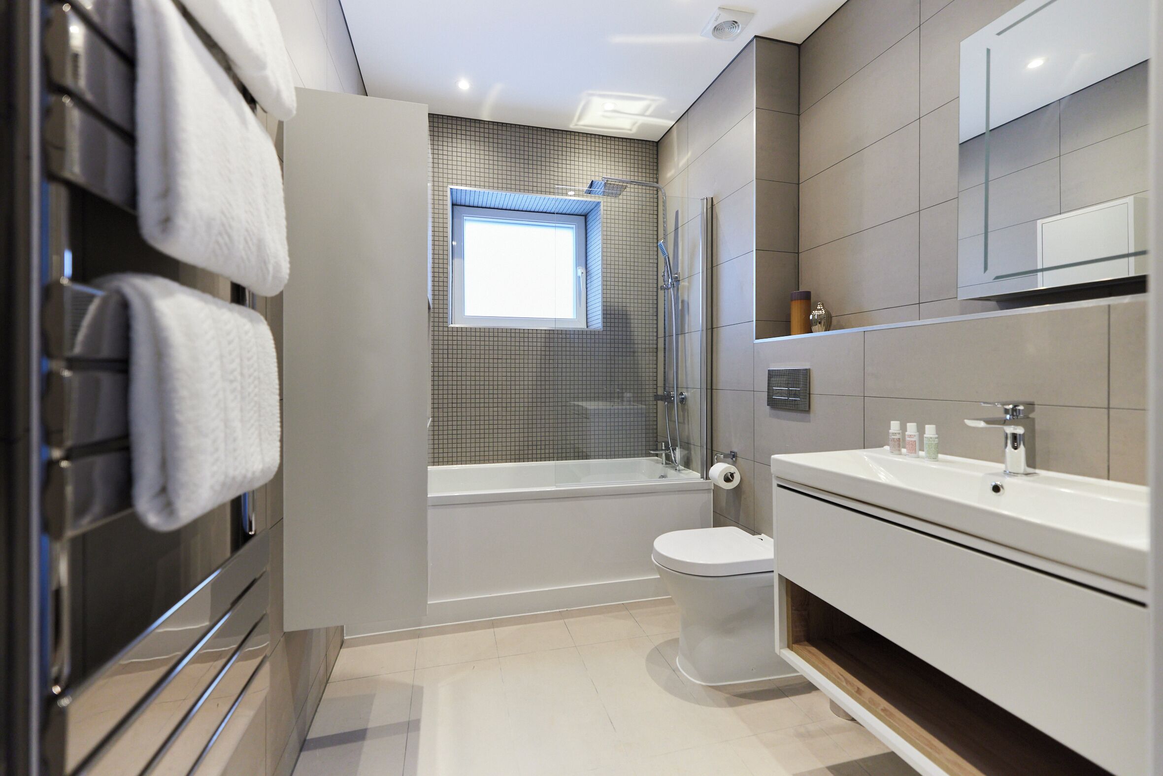 Een moderne badkamer met een bad, toilet en wastafel.
