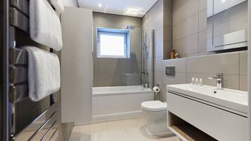 Een moderne badkamer met een bad, toilet en wastafel.