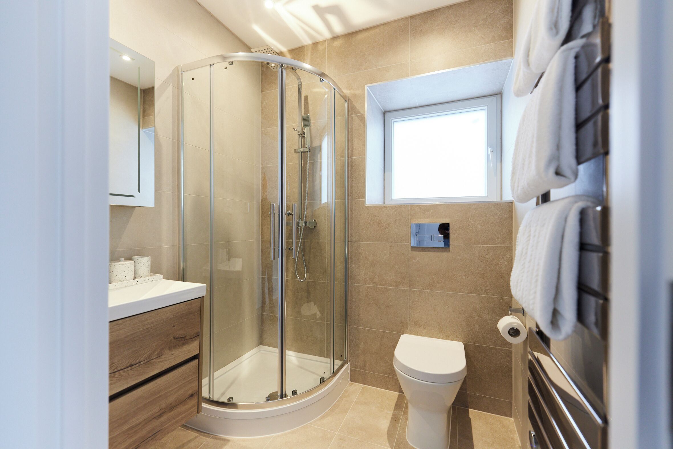 Un baño moderno con ducha de vidrio, inodoro y tocador con espejo.