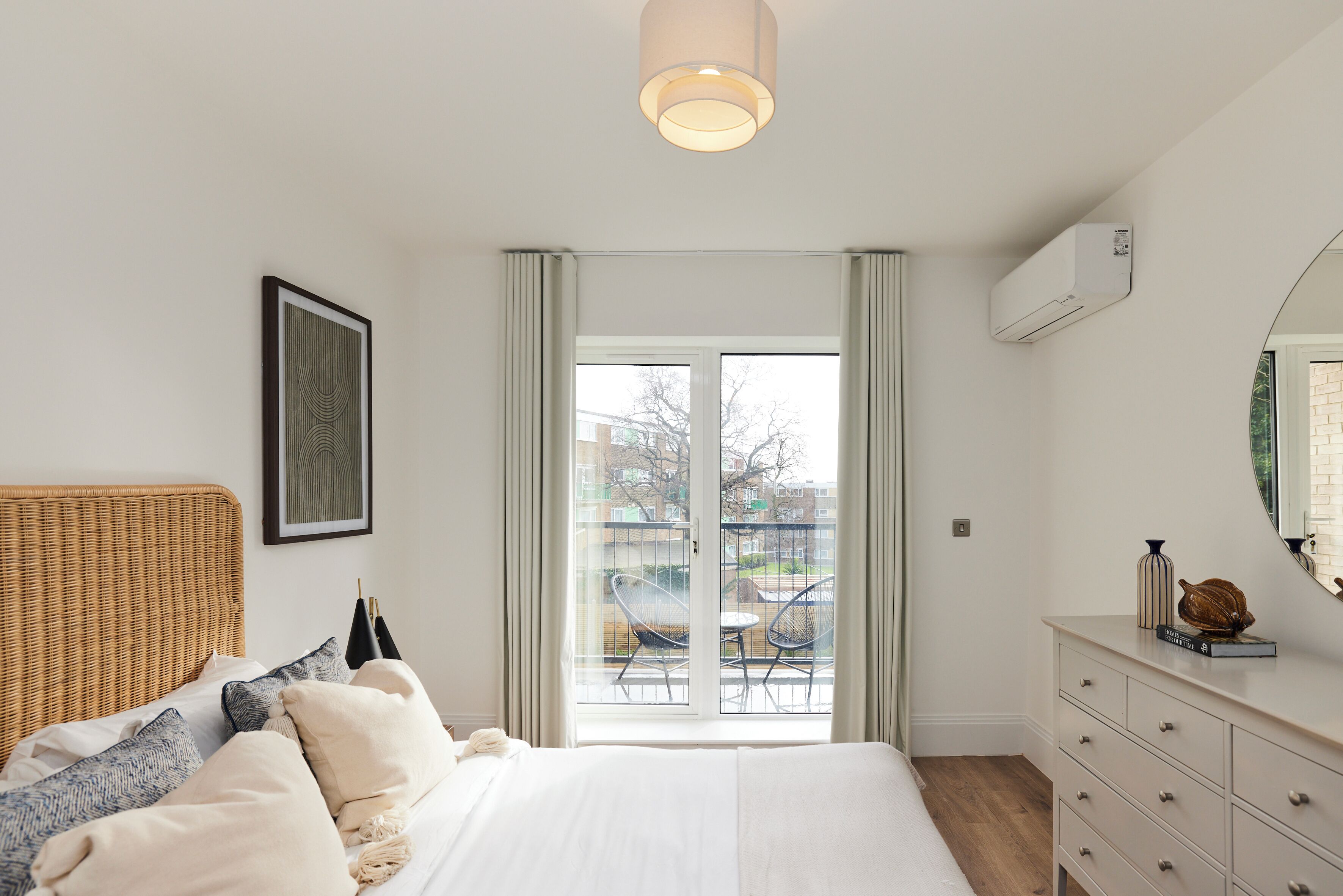 A bedroom with a bed, a dresser, a mirror, and a window with a view of the outside.