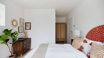 Un dormitorio con cama, cómoda y una planta en maceta.