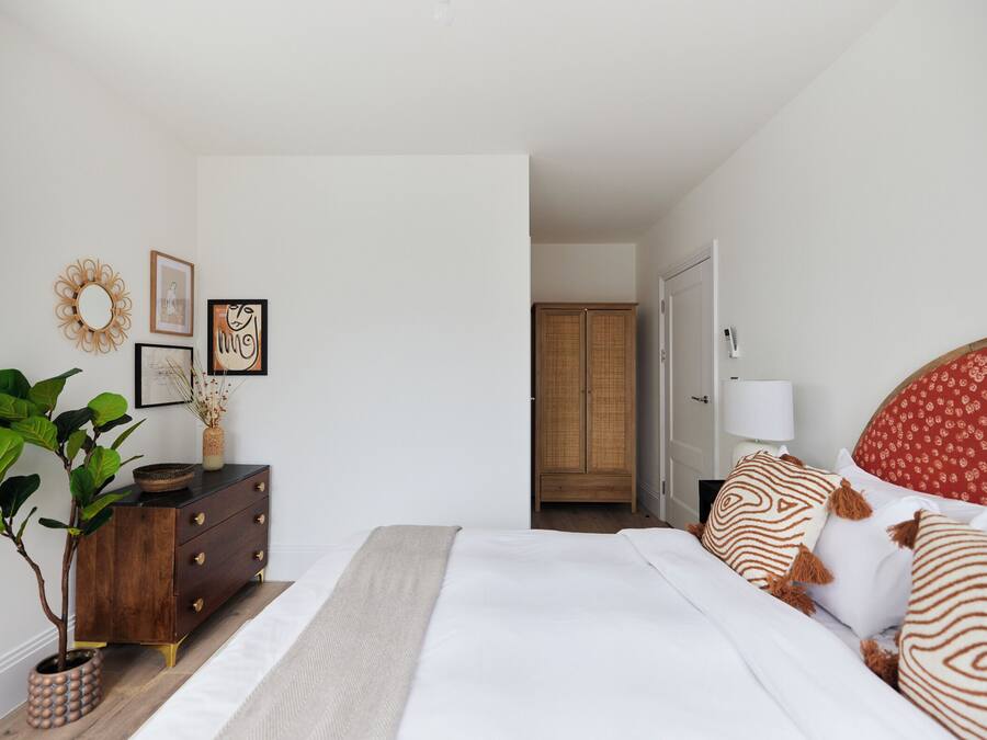 Un dormitorio con cama, cómoda y una planta en maceta.