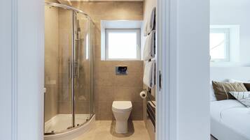 A modern bathroom with a glass shower enclosure, a toilet, and a small window.
