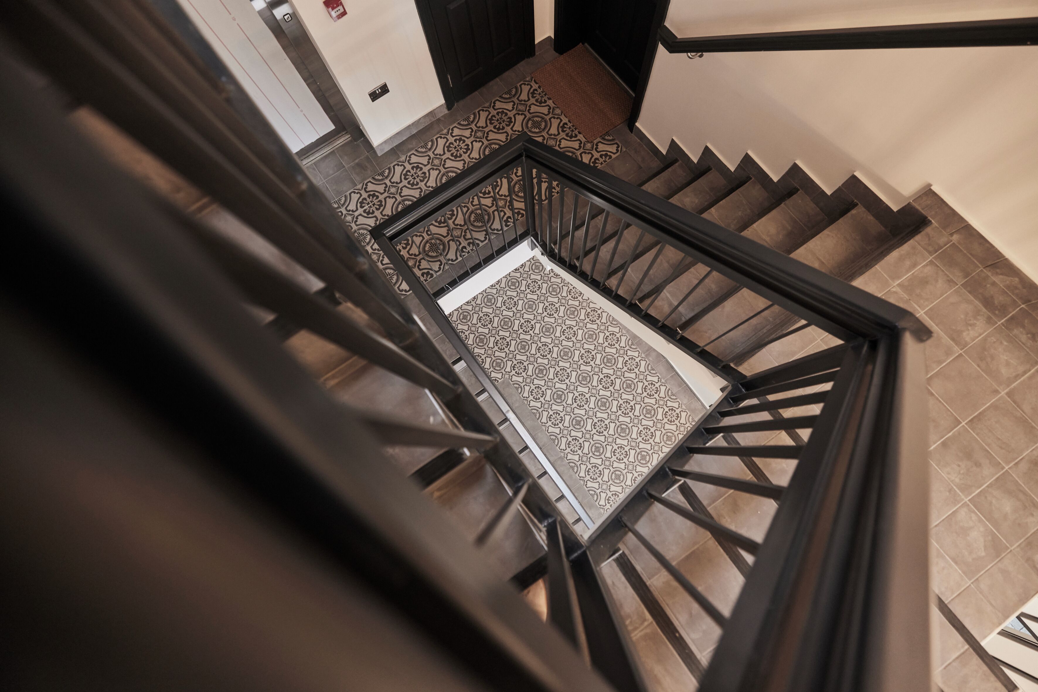 A staircase with a patterned carpet and a wooden handrail.