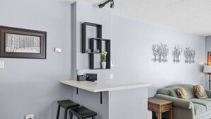 Ein modernes Wohnzimmer mit grauer Wand, einem weißen Regal, einer grauen Couch und einem kleinen Holztisch.