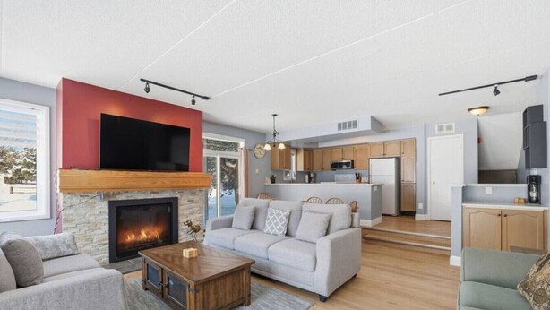 Ein modernes Wohnzimmer mit Kamin, grauen Sofas und einem Holztisch.