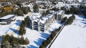 Ein schneebedecktes Wohngebiet mit modernen Häusern, einer Skipiste und freiem Blick auf die umliegende Landschaft.