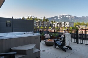 A rooftop terrace with a hot tub, seating area, and a fire pit. - Monashee Meadows in Mackenzie Village (Revelstoke)