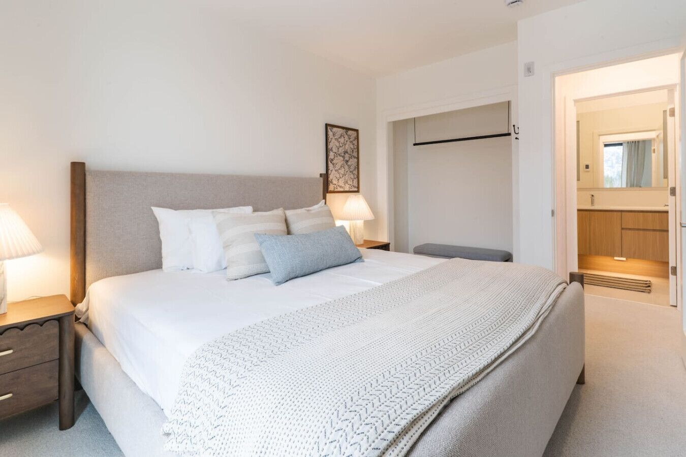 A neatly arranged bedroom with a bed, bedside tables, a bench, and a wardrobe.