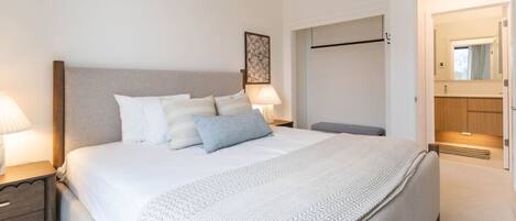 A neatly arranged bedroom with a bed, bedside tables, a bench, and a wardrobe.