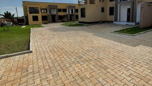 A modern building with a paved courtyard, multiple entry points, and a flat roof.