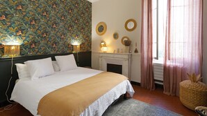 A bedroom with a bed, a fireplace, wall decor, and curtains. - Charming Apartment in the Heart of Ajaccio (Ajaccio)