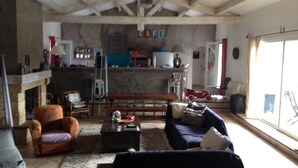 A living room with a fireplace, a sofa, a coffee table, and a dining area with a table and chairs. - Charming Waterfront Villa in Pietrosella, Corsica (Pietrosella)