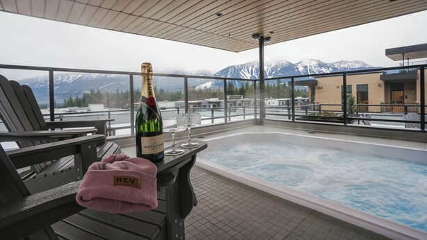 Eine Dachterrasse mit Whirlpool, Sitzgelegenheit und einer Flasche Champagner.