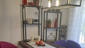 A dining area with a long table, two chairs, a small heater, and shelves with decorative items. - ALBIR, apartment for 4 pers., ground floor with garden, 100m to the beach, super pool, air conditioning (L’Alfàs del Pi)