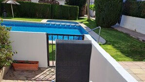 A patio area with a pool, stone flooring, and a black chair. - ALBIR, apartment for 4 pers., ground floor with garden, 100m to the beach, super pool, air conditioning (L’Alfàs del Pi)