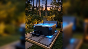 Ein mit einer Abdeckung versehenes Whirlpool, umgeben von einem Garten mit einer gepflasterten Fläche.