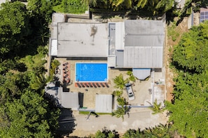 Eine Übersichtsansicht eines Grundstücks mit Swimmingpool, überdachter Terrasse und einem in der Nähe geparkten Auto.