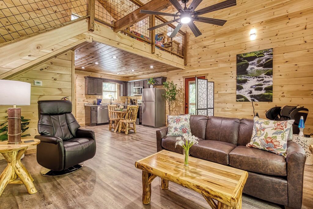 A spacious wooden cabin interior with a dining area, a living room with a sofa and coffee table, and a kitchen.