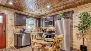 Una cocina con armarios de madera, electrodomésticos de acero inoxidable y una mesa de comedor con sillas de madera.