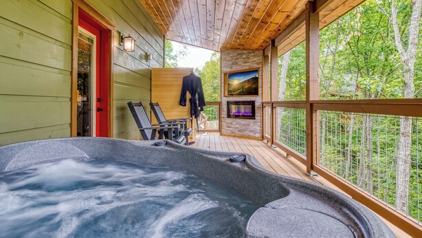 Un jacuzzi en una terraza de madera con vistas al bosque.