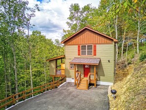 Eine kleine Holzhütte mit einer roter Tür, einer Veranda und einer Holztreppe, die zum Eingang führt.