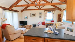 A cozy living room with a television, sofa, and a dining area with a kitchen counter. - Casa Mia (Goodwick)