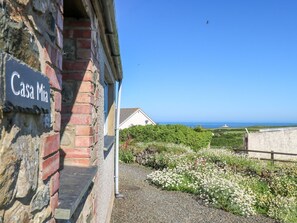 Un edificio con un cartel de 'Casa Mia', un camino de grava y vistas al mar y al paisaje distante.