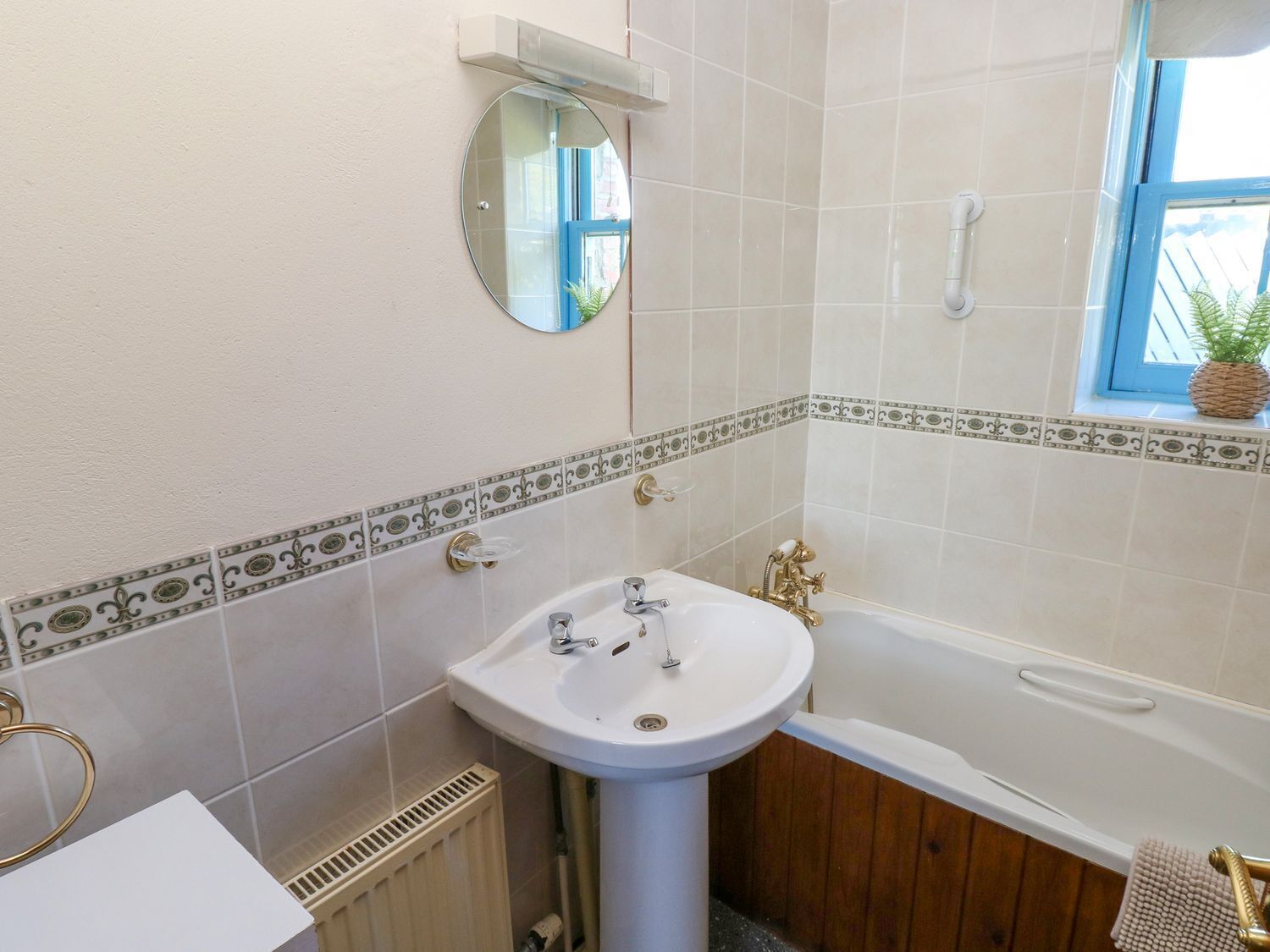 Une salle de bain avec un lavabo blanc, une baignoire et une fenêtre donnant sur un beau paysage.