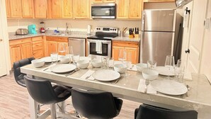 Cocina moderna con armarios de madera, electrodomésticos de acero inoxidable y una zona de comedor preparada para cuatro.