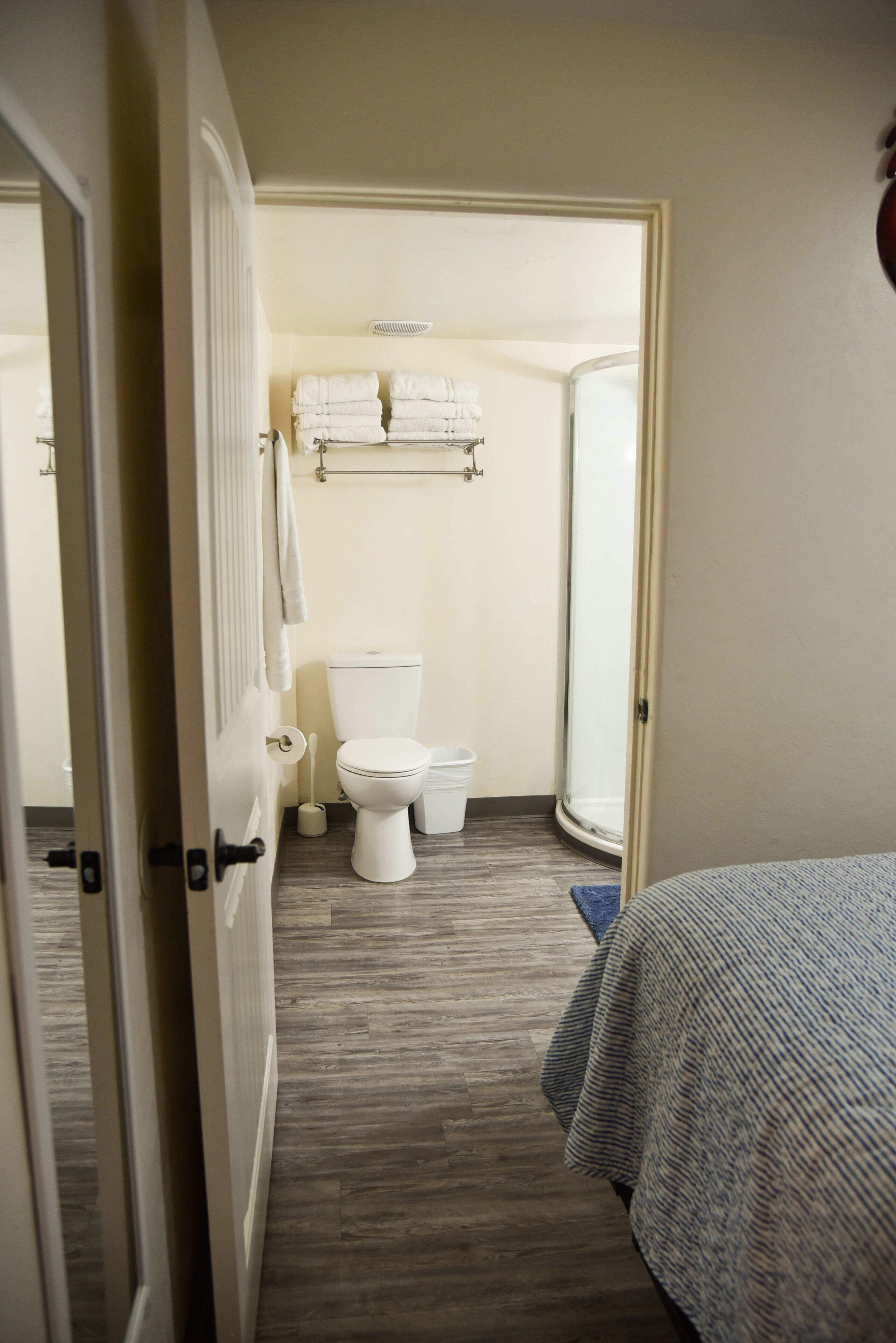 A hotel room with a bed, a bathroom with a toilet, and a shower.