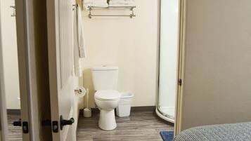 A hotel room with a bed, a bathroom with a toilet, and a shower.
