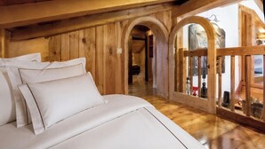 A wooden interior with a bed, arched doorways, and a view through a glass door. - Authentic Chalet in Chamonix-Mont-Blanc (Chamonix-Mont-Blanc)