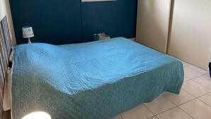 Una camera da letto con un letto, una finestra, un'opera d'arte a parete e un comodino con una lampada.