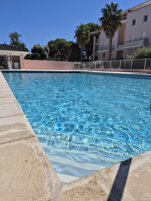 A swimming pool with clear blue water, surrounded by a stone deck. - Large T4 with pool, terrace and beach on foot (Fréjus)