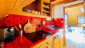Una cocina con salpicadero de baldosas rojas, armarios de madera y una estufa negra.