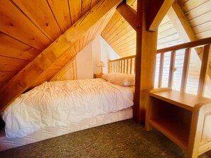 A cozy attic bedroom with a wooden sloped ceiling, a single bed, a nightstand, and a small wooden shelf. - Ski nest with large balcony (La Salle-les-Alpes)