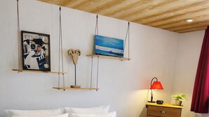 Een slaapkamer met een bed, een dressoir, een rode lamp en wanddecoratie.