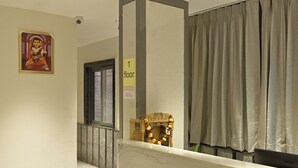 Ein Hotel-Rezeptionsbereich mit einer Marmor-Theke, einem Deckenventilator, einem gerahmten Bild an der Wand und einem Schild mit der Angabe der Etage.
