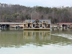 A houseboat with a deck, outdoor seating, and a covered area.