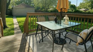 A wooden deck with a table and chairs, an umbrella, and a lantern. -  Hidden Gem Steps From River, Restos, Cafés, Parks (Windsor)