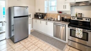 A modern kitchen with stainless steel appliances, white cabinetry, and a tiled floor. -  Hidden Gem Steps From River, Restos, Cafés, Parks (Windsor)