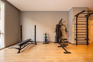 Gimnasio con banco, estante para pesas y barra de dominadas.