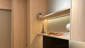 A modern, compact room with built-in wooden cabinets, a white desk, and a shelf with decorative items. - Luxury studio apartment, do everything on foot! (São Caetano do Sul)