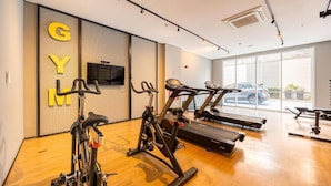 A gym with stationary bikes, treadmills, and a television on the wall. - Luxury studio apartment, do everything on foot! (São Caetano do Sul)