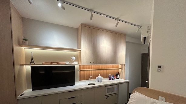 A modern hotel room with a kitchenette, a bed with white linens, and a small decorative Eiffel Tower model. - Luxury studio apartment, do everything on foot! (São Caetano do Sul)